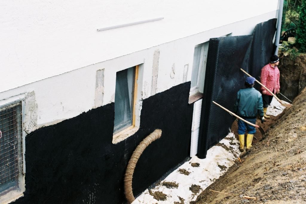 Zwei Männer arbeiten an der Seite eines Gebäudes