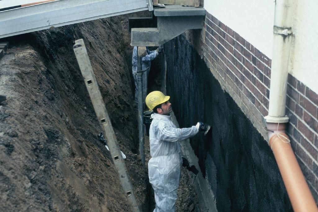Ein Mann mit Schutzhelm arbeitet an einer Ziegelmauer.