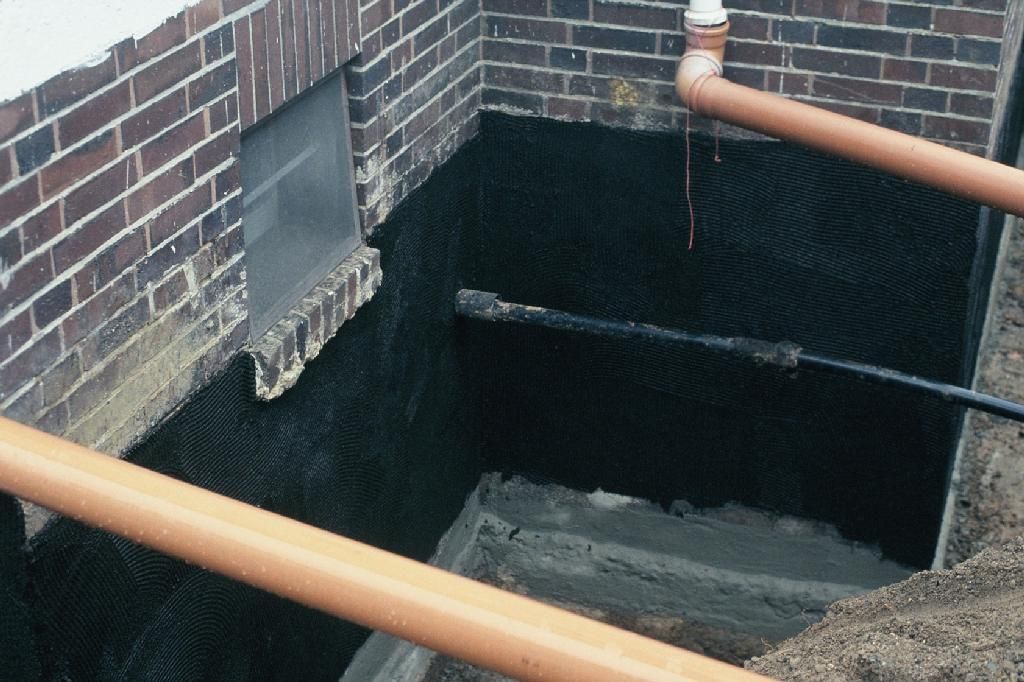 Ein Loch in einer Ziegelwand, aus dem Rohre herauskommen