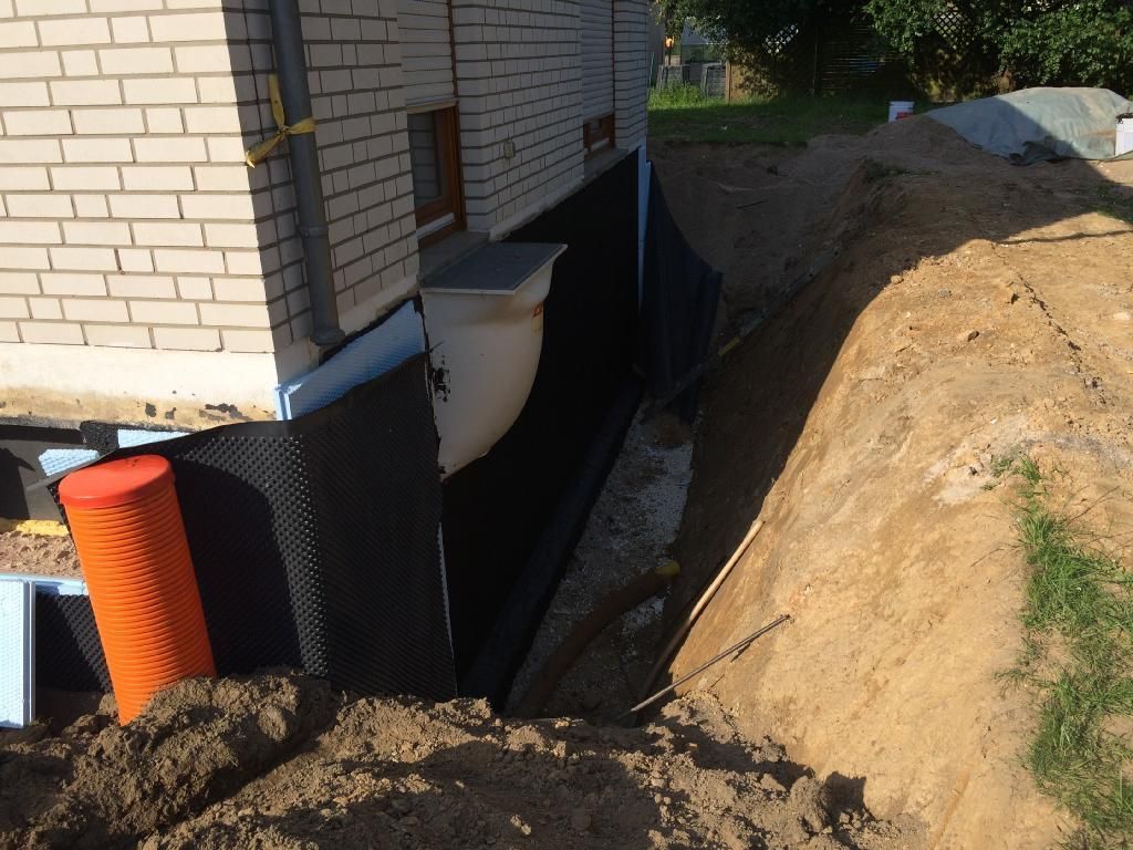 Ein weißes Backsteingebäude mit einem Loch im Boden davor