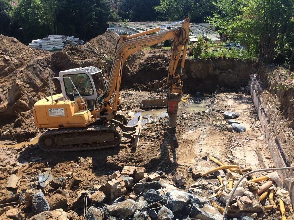 Ein gelber Bagger gräbt ein Loch in den Boden.