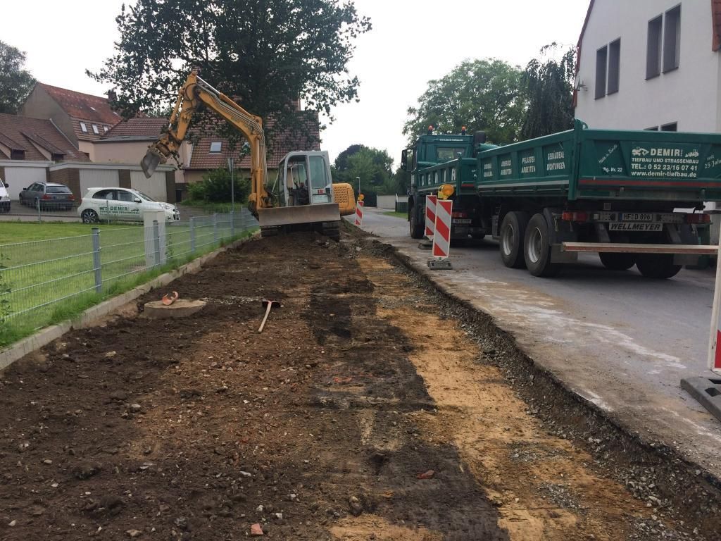 Neben einem Muldenkipper gräbt ein Bagger ein Loch in den Boden.