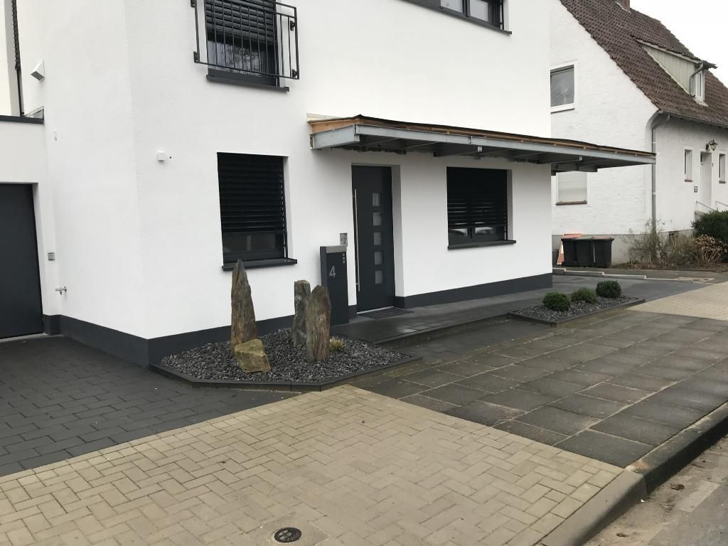 Ein weißes Haus mit einer schwarzen Tür und einem schwarzen Garagentor