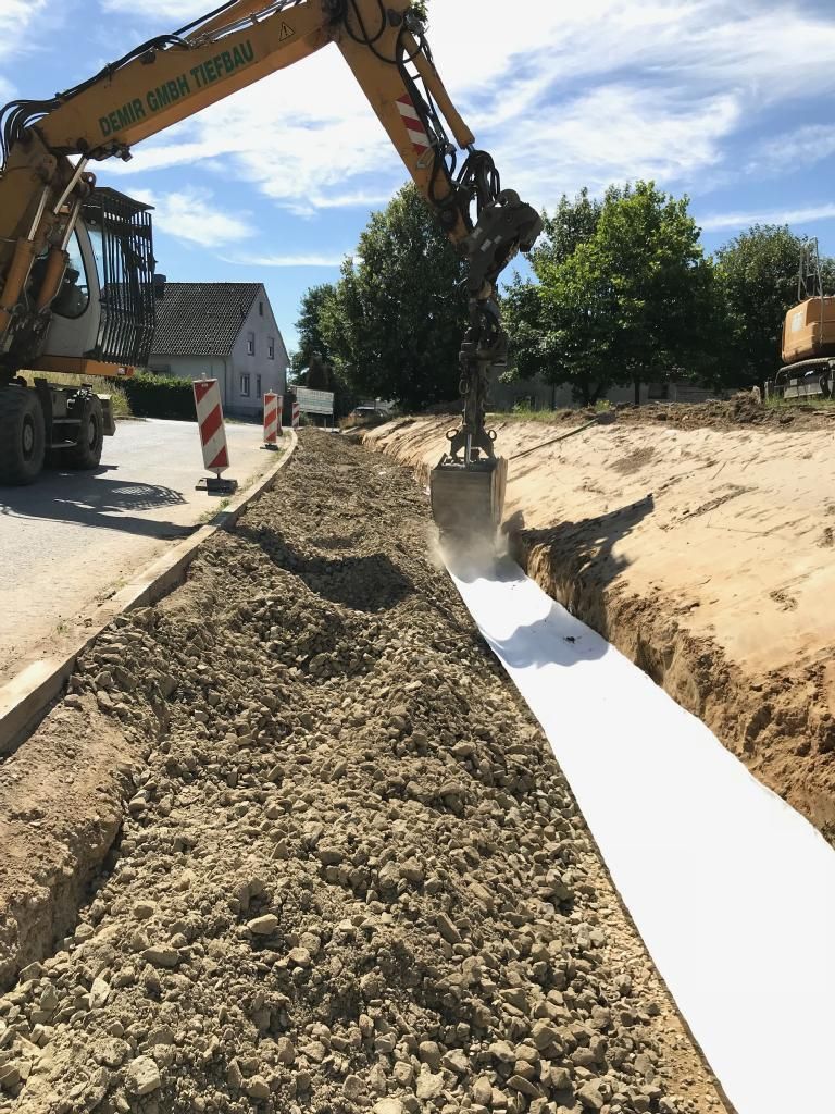 Ein gelber Bagger gräbt ein Loch in den Boden.