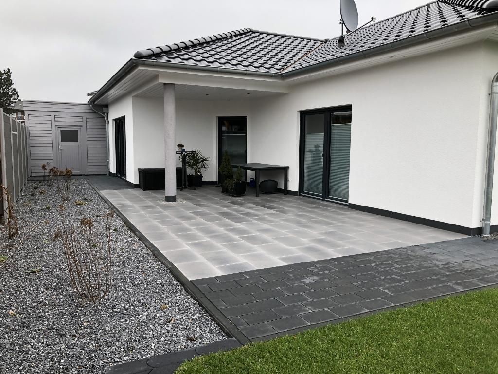 Ein weißes Haus mit einer Terrasse davor.