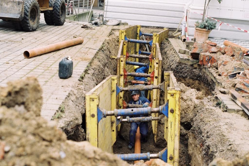 Ein Mann arbeitet an einem Rohr in einem Graben