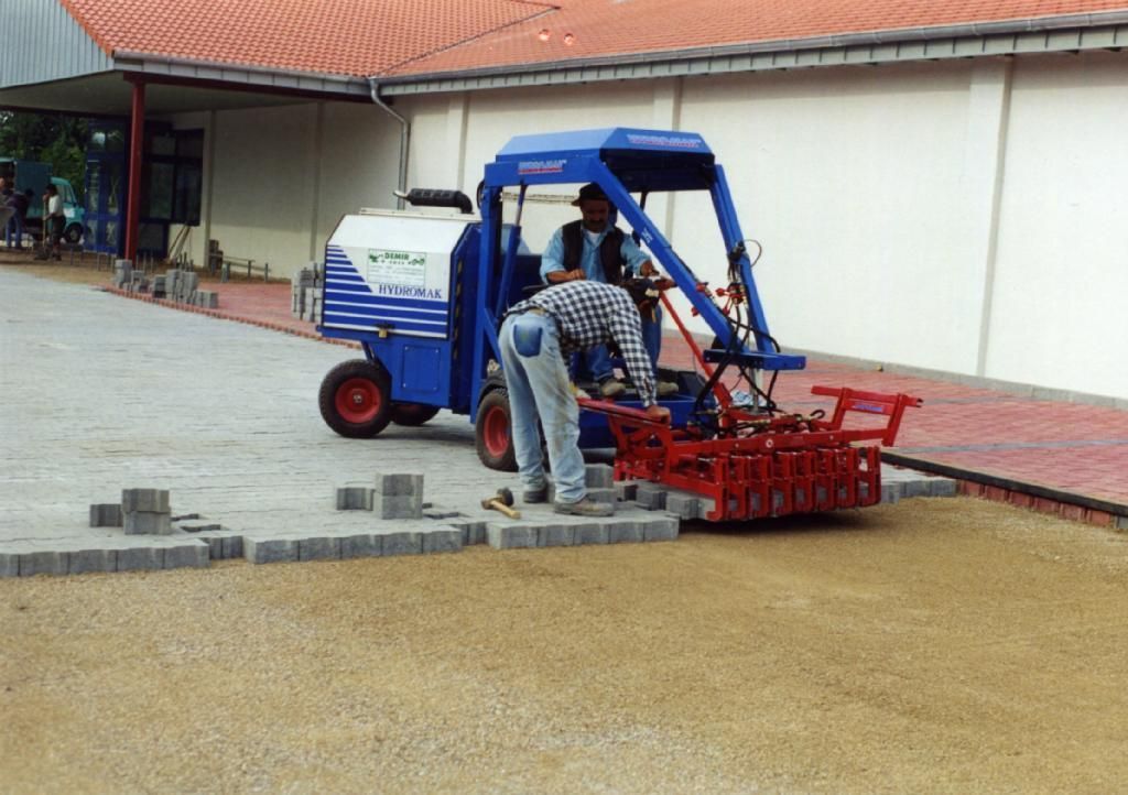 Ein blau-rotes Fahrzeug wird zum Verlegen von Ziegeln eingesetzt