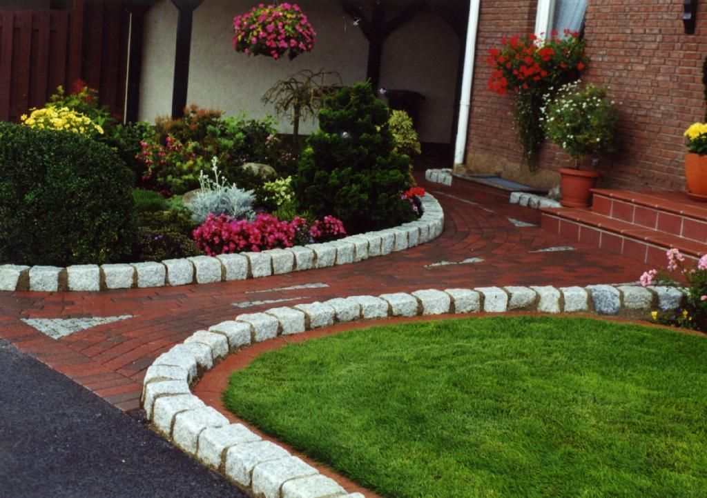 Eine gepflasterte Auffahrt mit einem üppigen grünen Rasen und Blumen