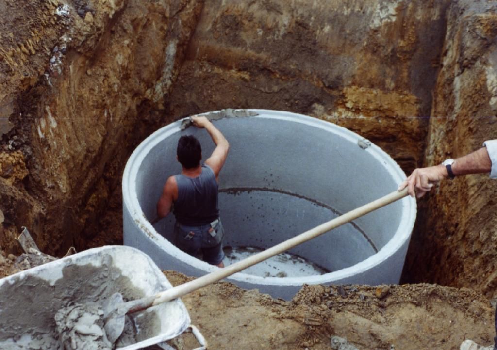 Zwei Männer arbeiten an einem großen Betonring im Dreck