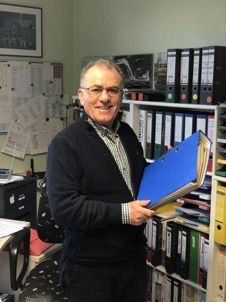 Ein Mann in einem Büro hält einen blauen Ordner