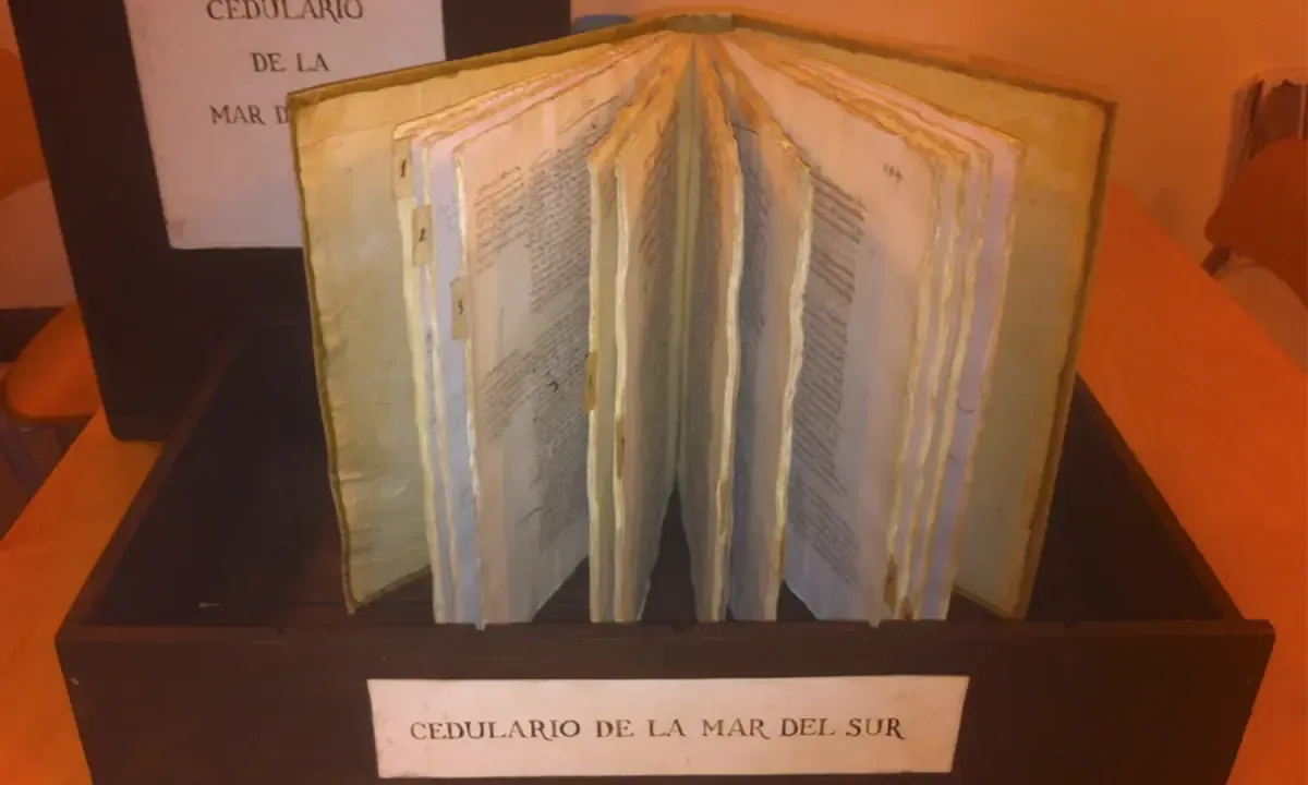 Libro antiguo abierto, expuesto en un museo. Estuche de madera marrón con etiqueta impresa.
