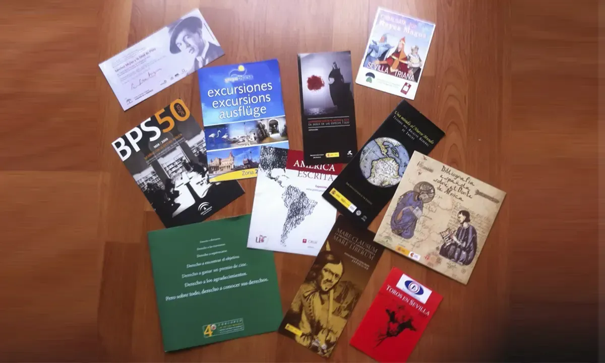 Folletos y panfletos variados de distintos tamaños, con texto e imágenes, esparcidos sobre una superficie de madera.