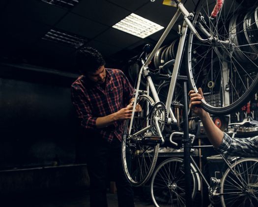 Dos hombres están trabajando en una bicicleta en un garaje.