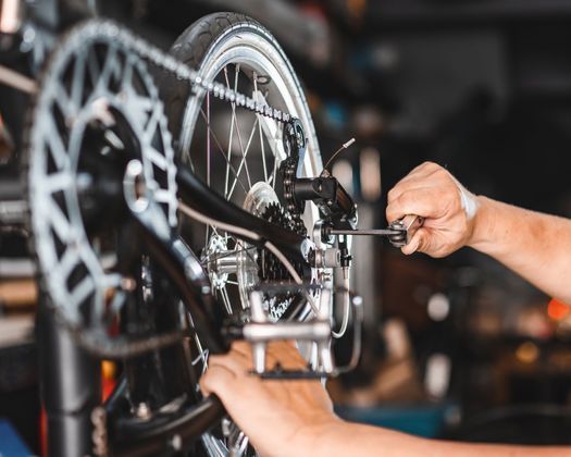 Una persona está arreglando una bicicleta con una llave inglesa.