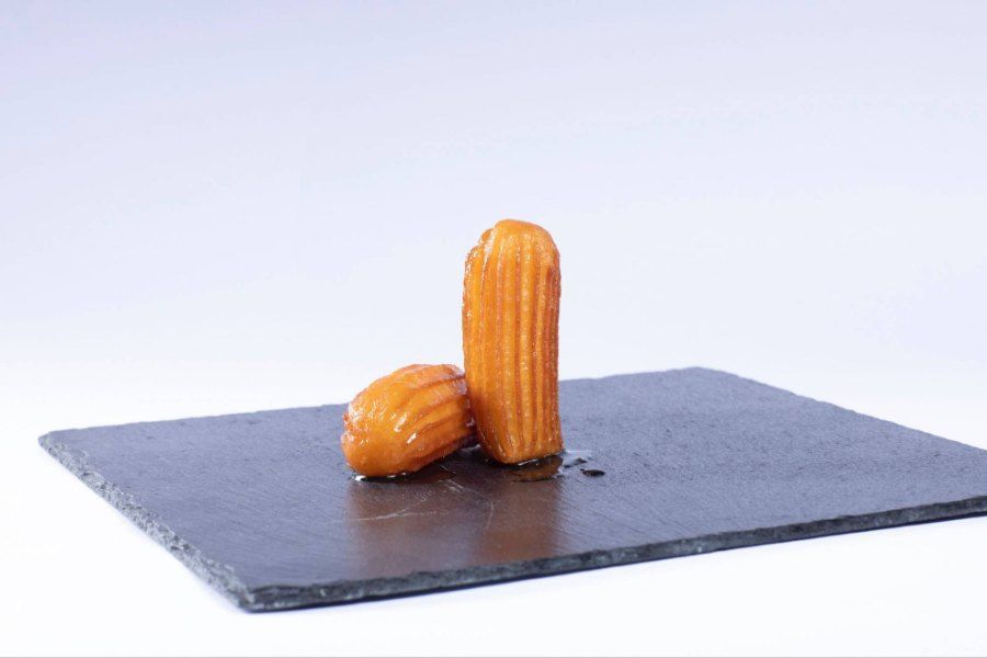 Ein paar Tullumba auf einem schwarzen Teller. Foto von der Burek House GmbH.