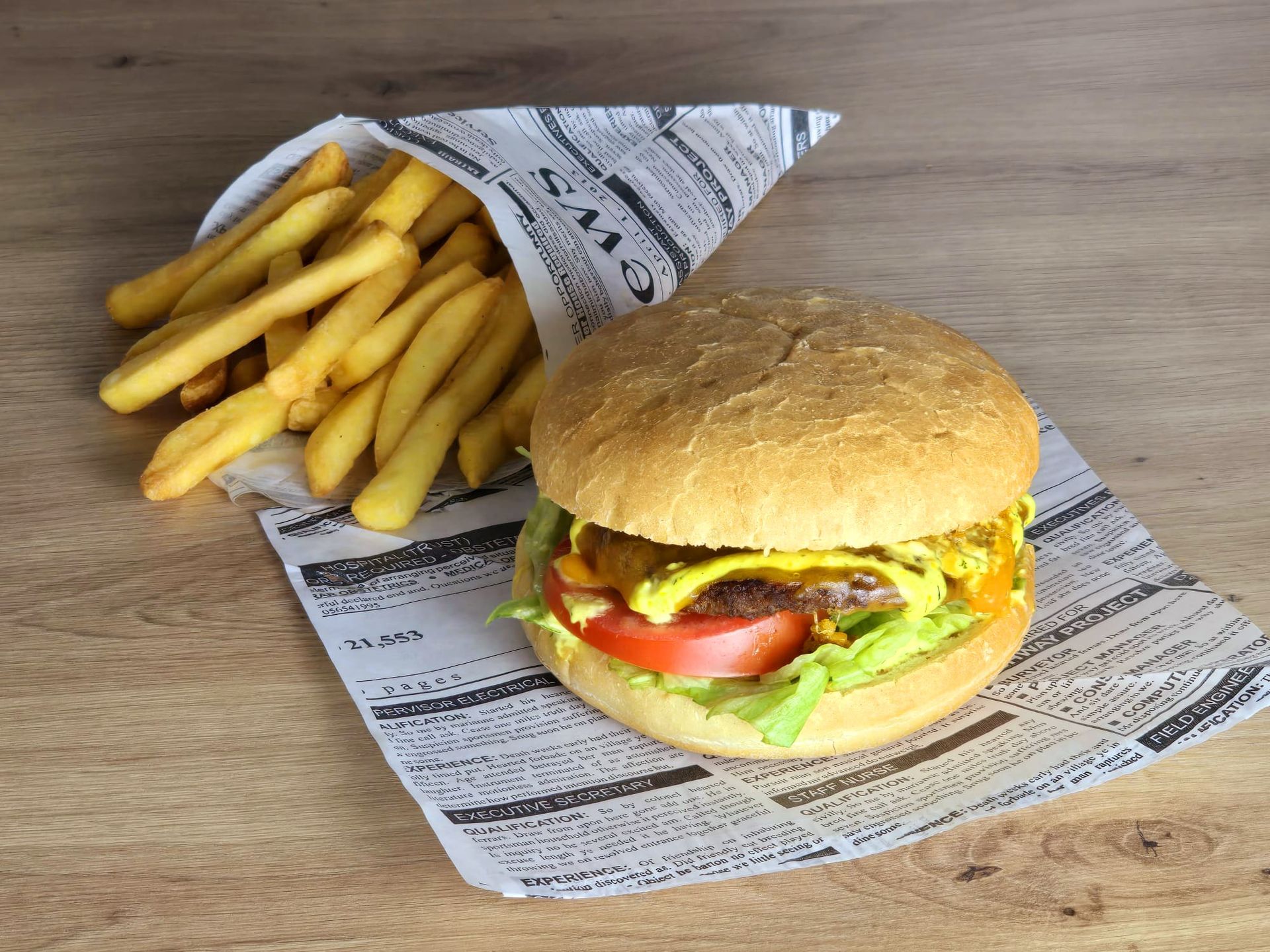 Ein Hamburger und Pommes Frites liegen auf einem Holztisch.