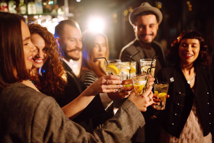 Eine Gruppe Leute stößt in einer Bar mit Drinks an.