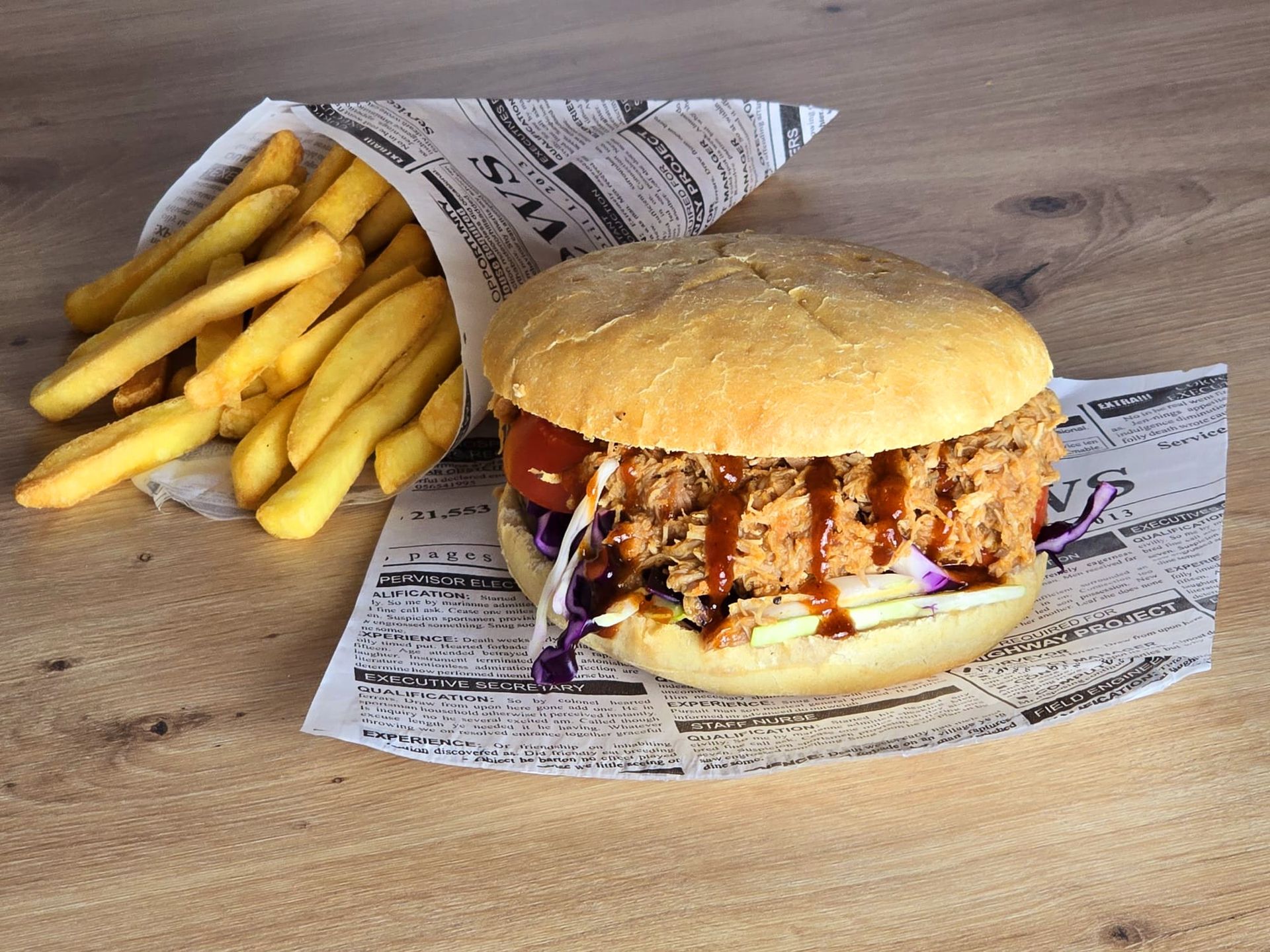 Ein Hamburger und Pommes Frites liegen auf einem Holztisch.