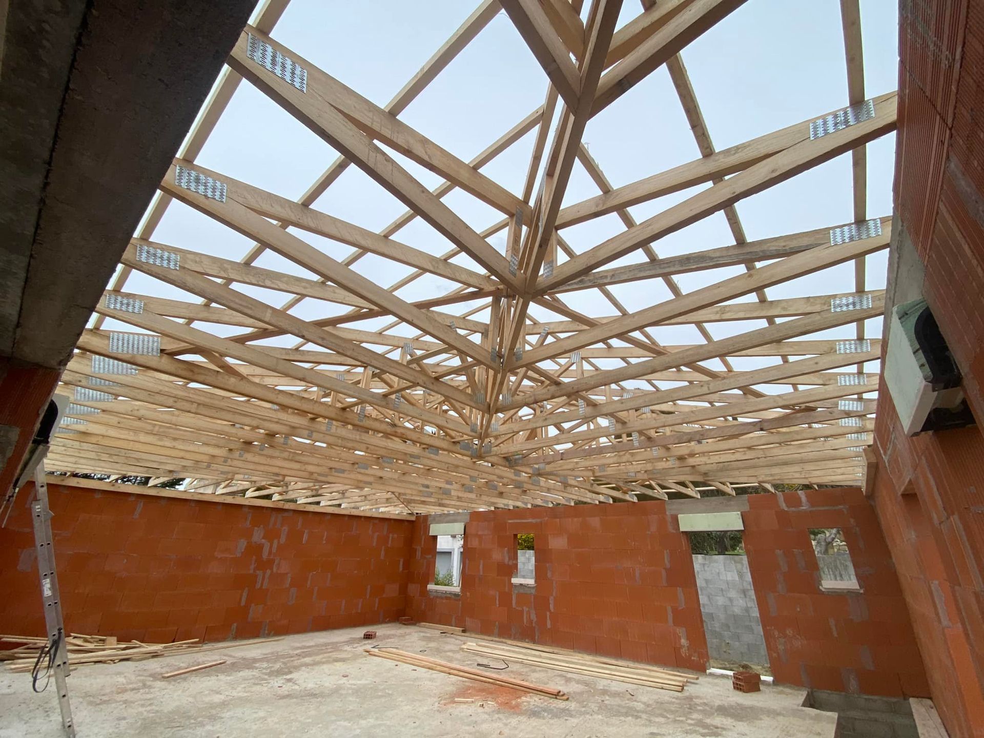 Construction de charpentes de toit en bois sur un bâtiment, présence d'ouvriers du bâtiment.