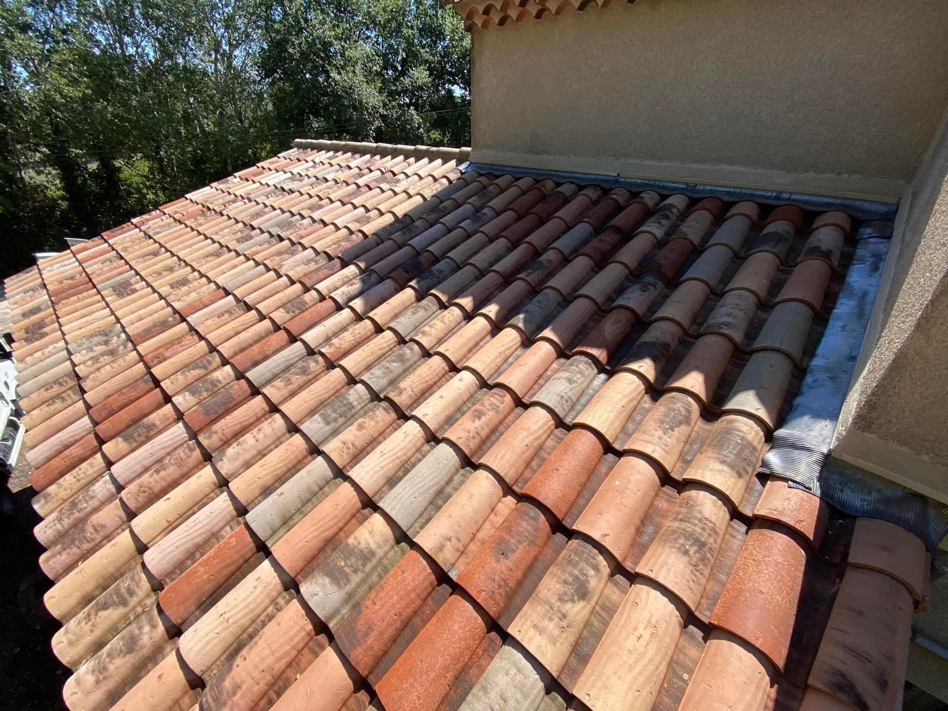 Toiture en tuiles de terre cuite rouge, aspect patiné. Cadre extérieur ensoleillé.