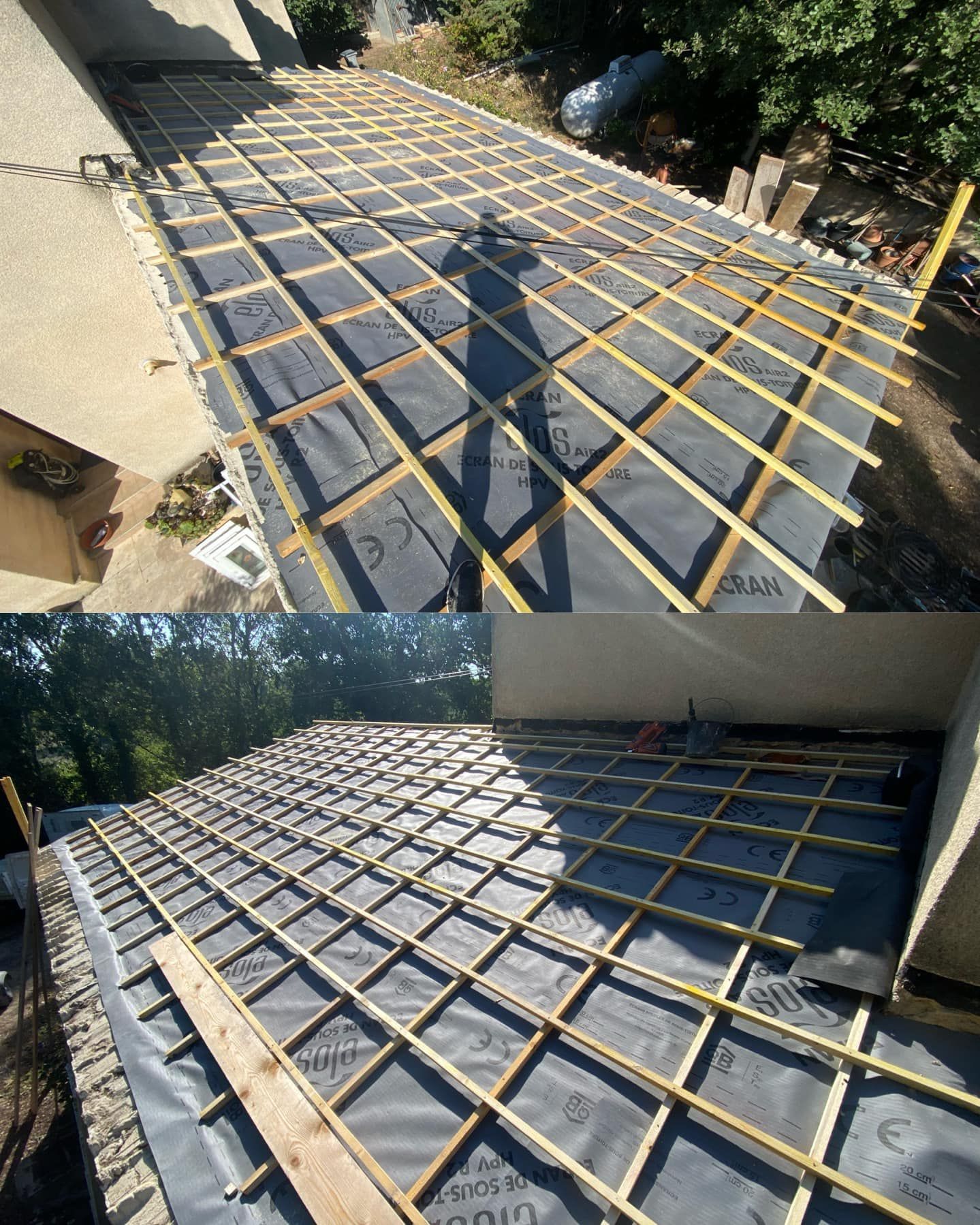 Toit en construction : poutres en bois, sous-couche noire et l'ombre d'une personne.