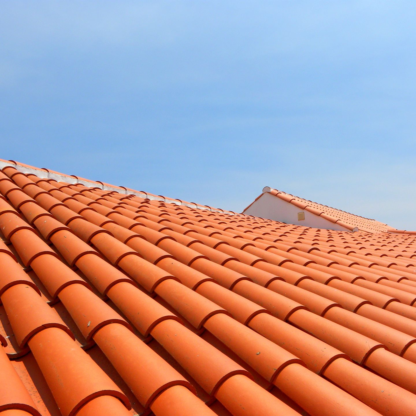 Des tuiles rouges en terre cuite se détachant sur un ciel bleu limpide.