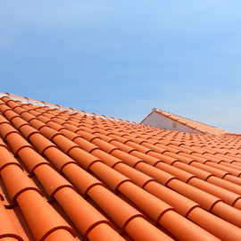 Des tuiles rouges en terre cuite se détachant sur un ciel bleu limpide.