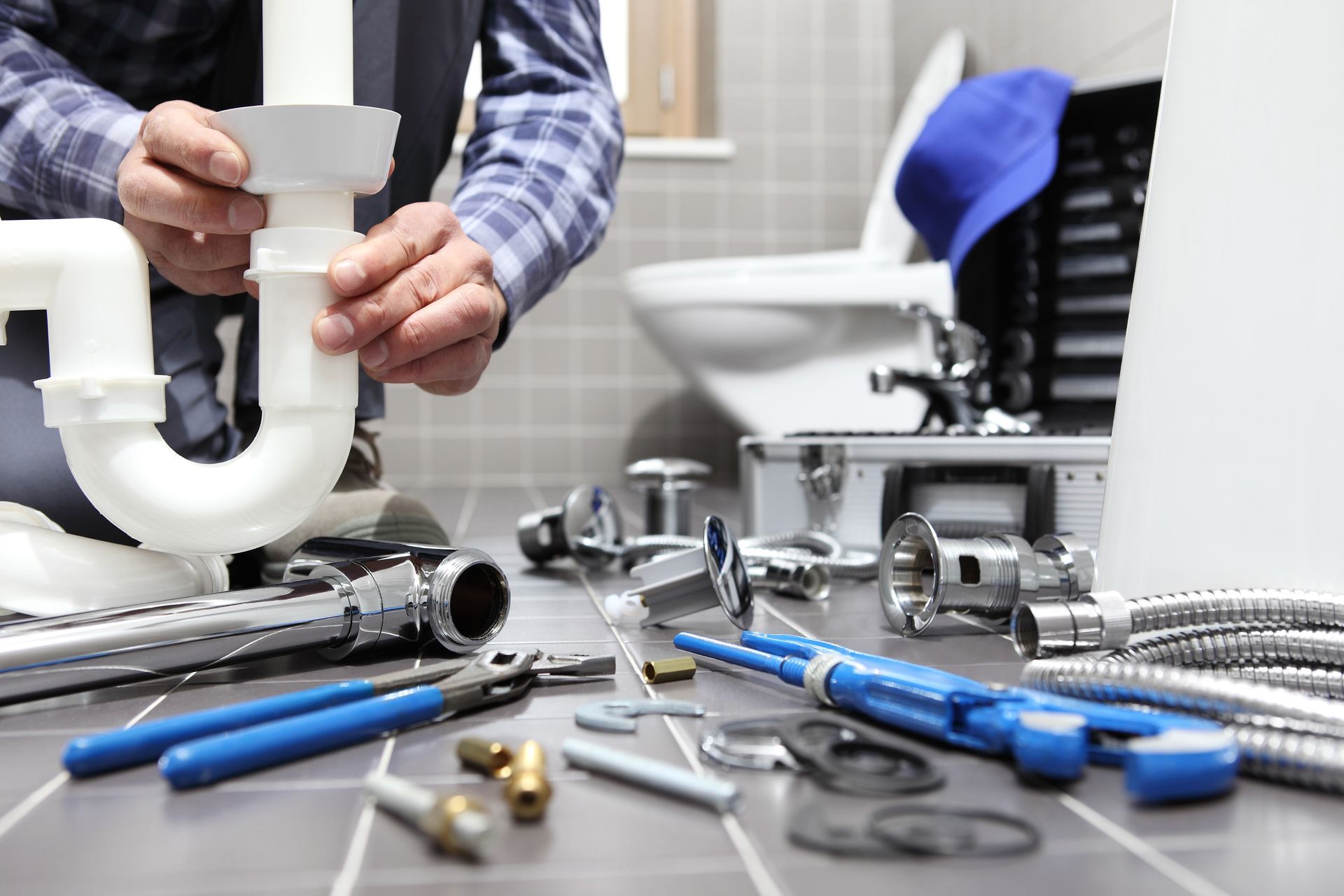 Plombier installant des tuyaux avec des outils dans une salle de bain, en se concentrant sur le système de drainage.