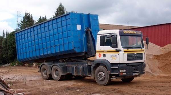 Un camión volquete azul está estacionado en un campo de tierra.
