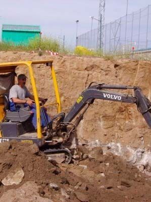 Un hombre conduce una excavadora Volvo en la tierra.