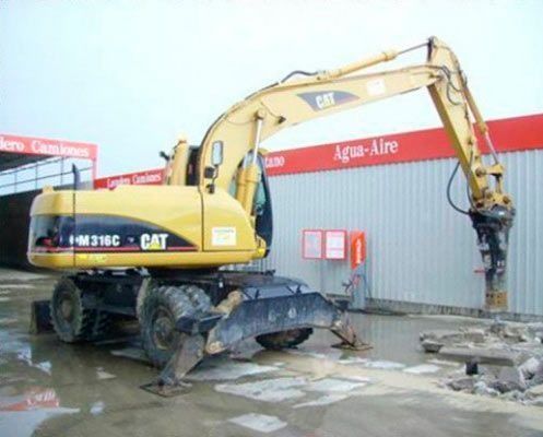 Una excavadora amarilla está estacionada frente a un edificio