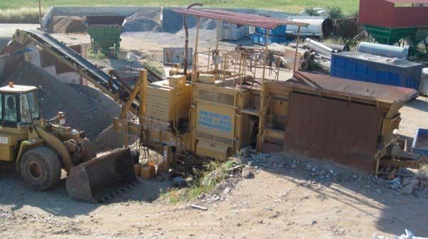 Una excavadora está moviendo tierra en un campo de tierra.