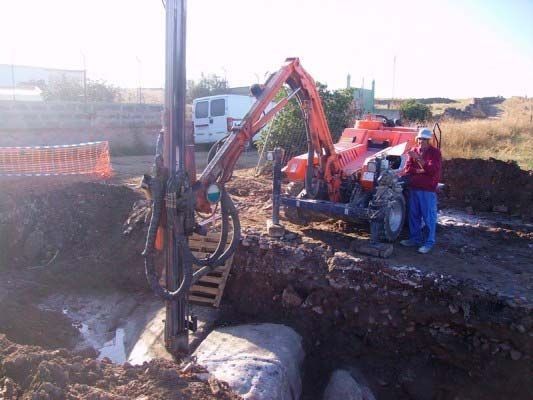 Un hombre está parado junto a una máquina en la tierra.