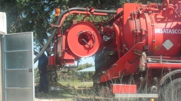 Un hombre está de pie junto a un camión de vacío rojo.