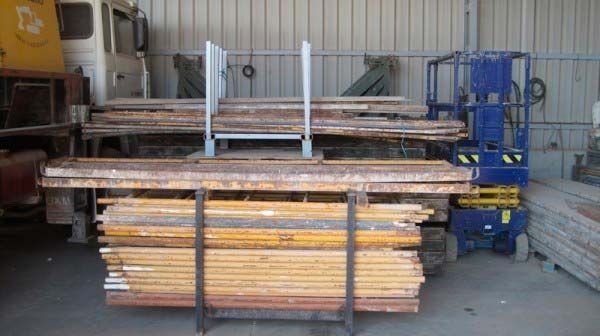 Una pila de madera se encuentra en un almacén al lado de una carretilla elevadora.