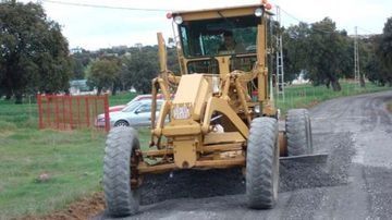 Un tractor amarillo conduce por un camino de tierra.