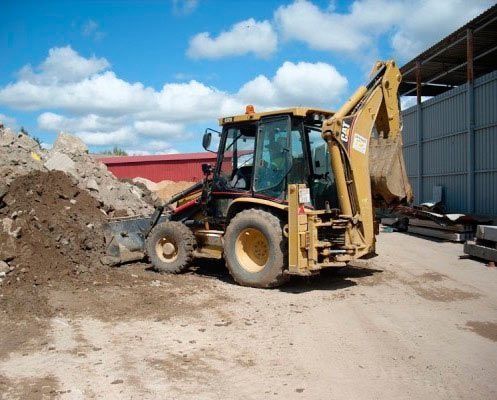 Una excavadora está estacionada frente a un montón de tierra.