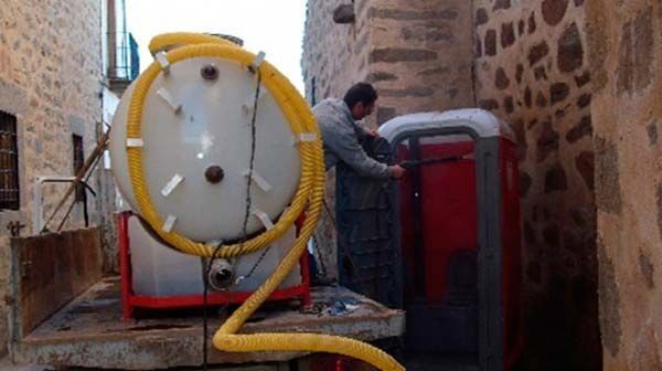 Un hombre está parado al lado de un camión con una manguera conectada a él.