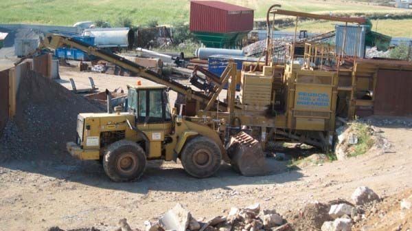 Una excavadora está moviendo una pila de rocas en una cantera.