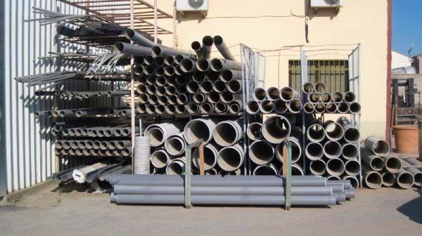 Un montón de tuberías están apiladas una encima de otra frente a un edificio.