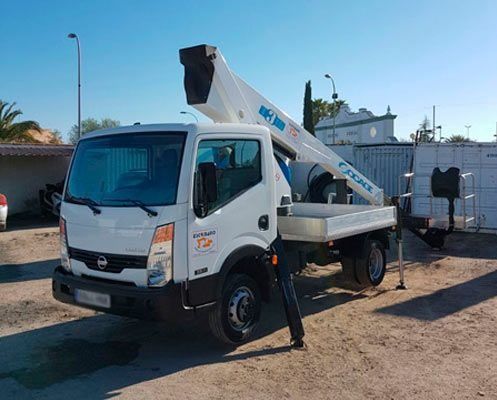 Un camión blanco con una grúa acoplada está estacionado en un estacionamiento.