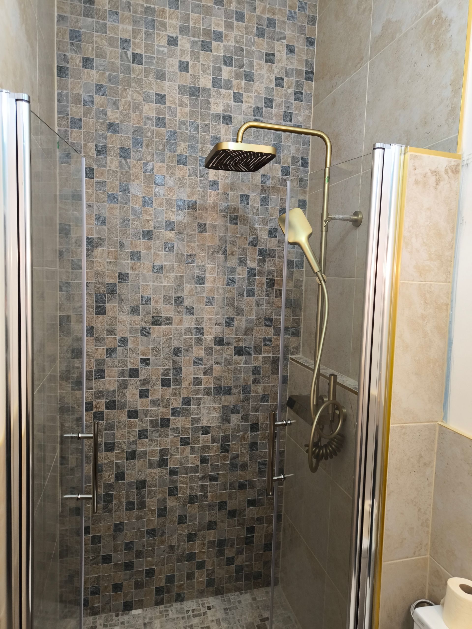 Douche avec un mur de fond décoré de mosaïques similiroche