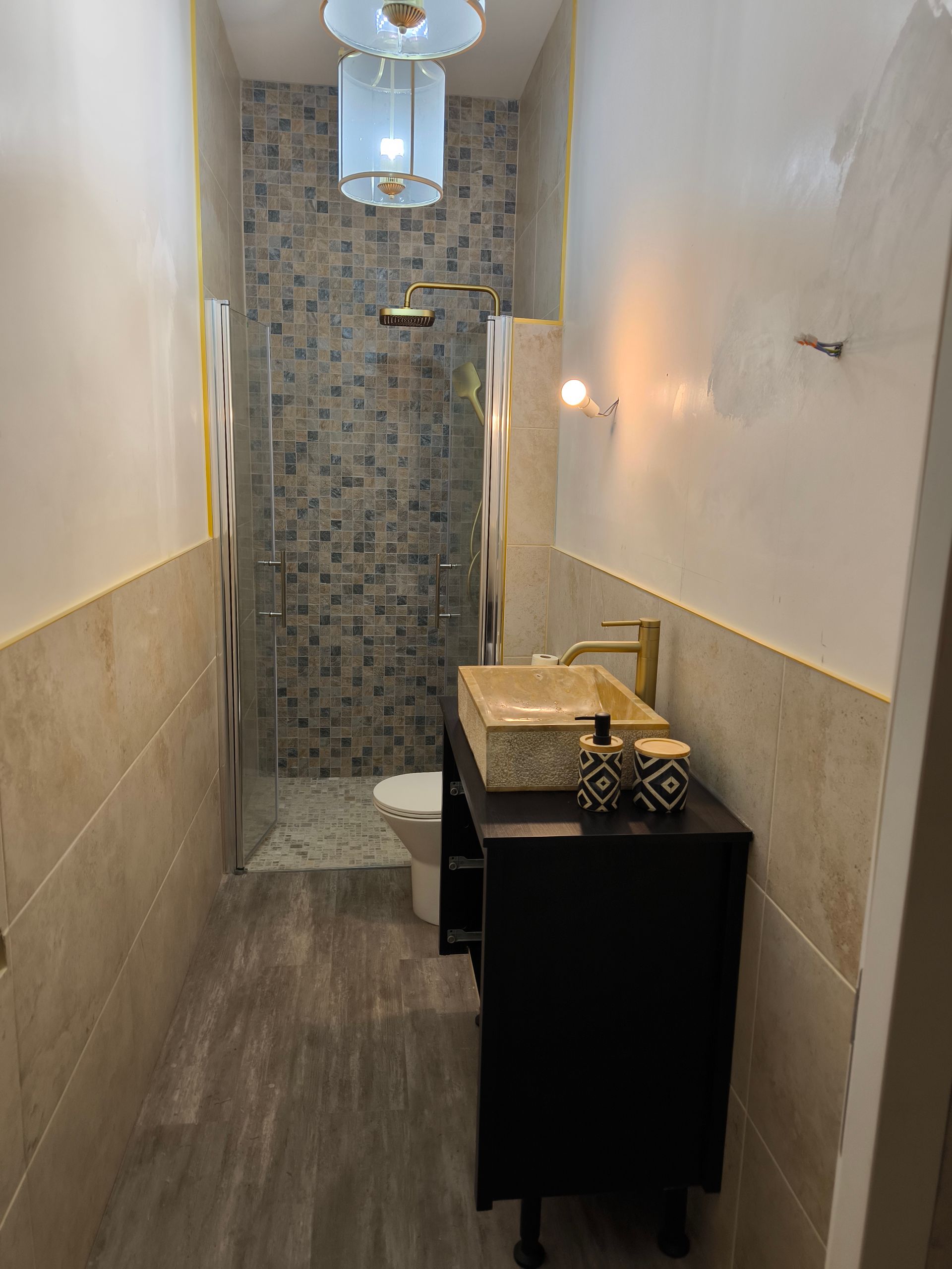 Salle de bains moderne avec une douche dotée de portes battantes vitrées et d'un pommeau simili-or