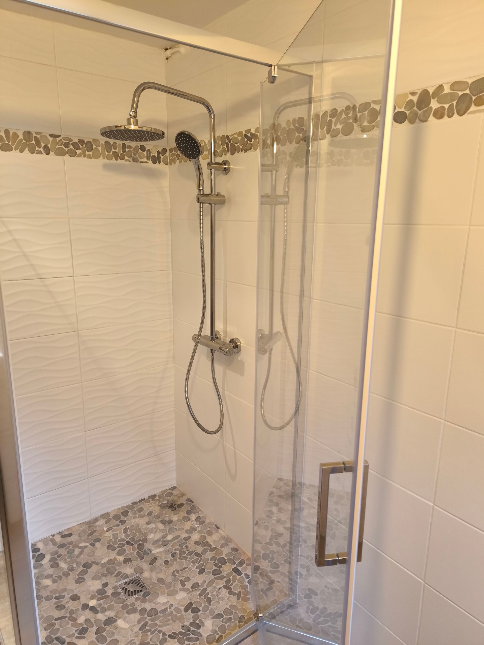 Douche avec portes en verre et sol en galets