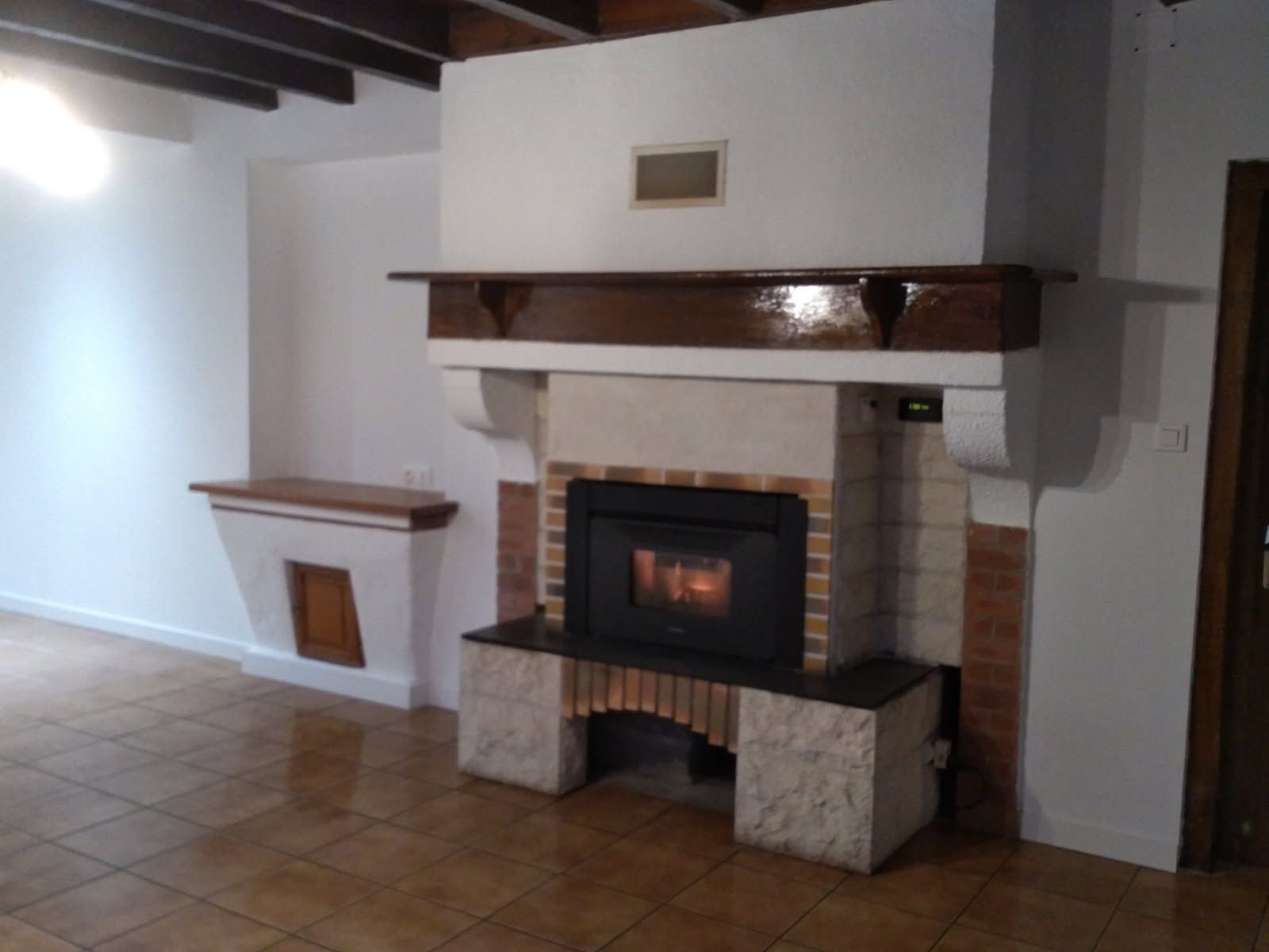 Cheminée avec un manteau brun foncé, un entourage en briques et un feu allumé.