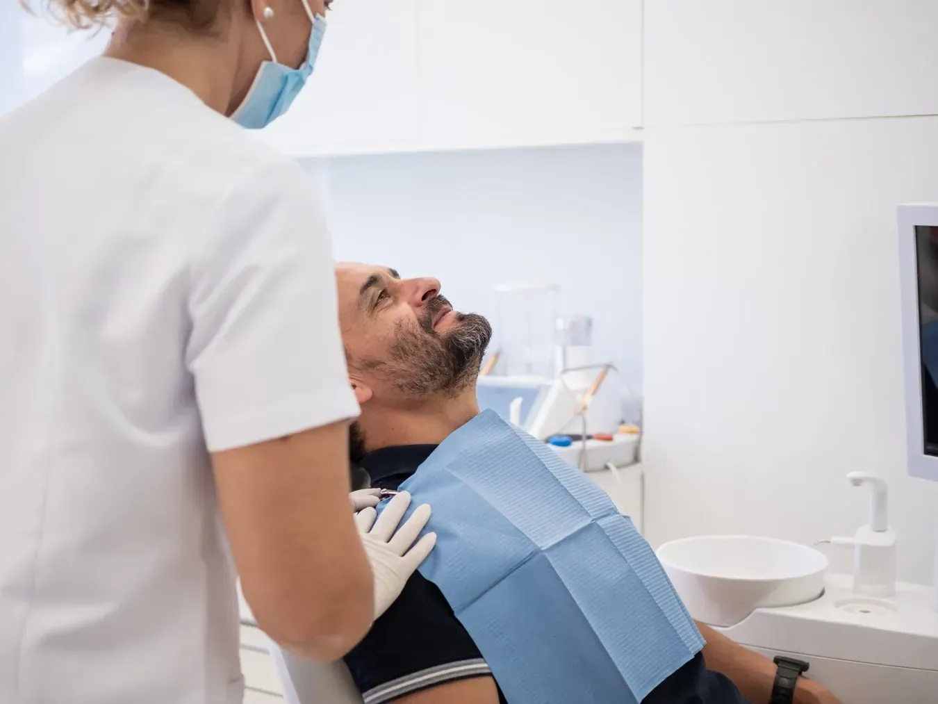 Dentista con mascarilla y guantes atendiendo a paciente en sillón dental.