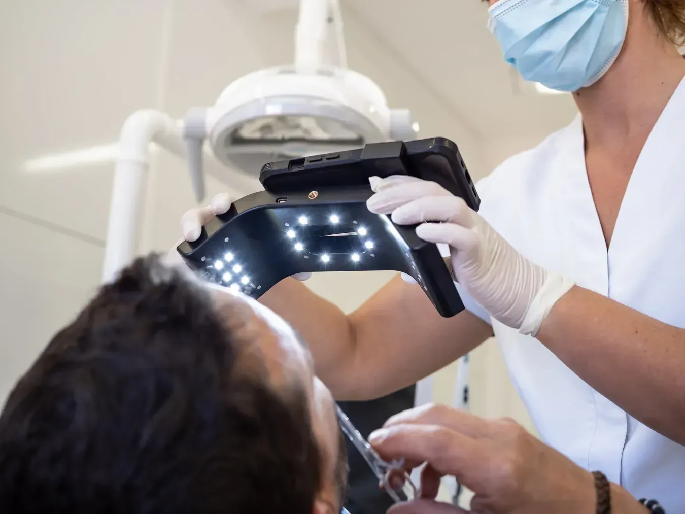 Dentista examinando los dientes de un paciente con una lámpara de mano y un espejo. En un entorno clínico.