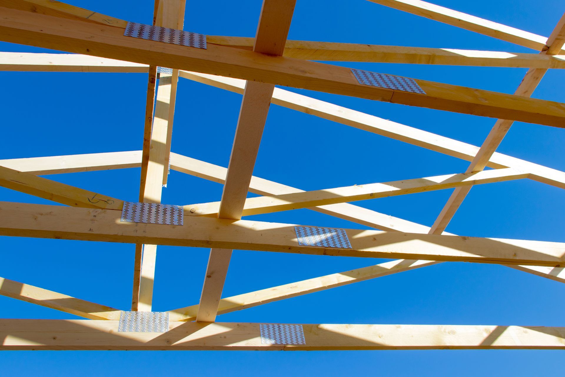 Charpente en bois en cours de construction, se détachant sur un ciel bleu éclatant