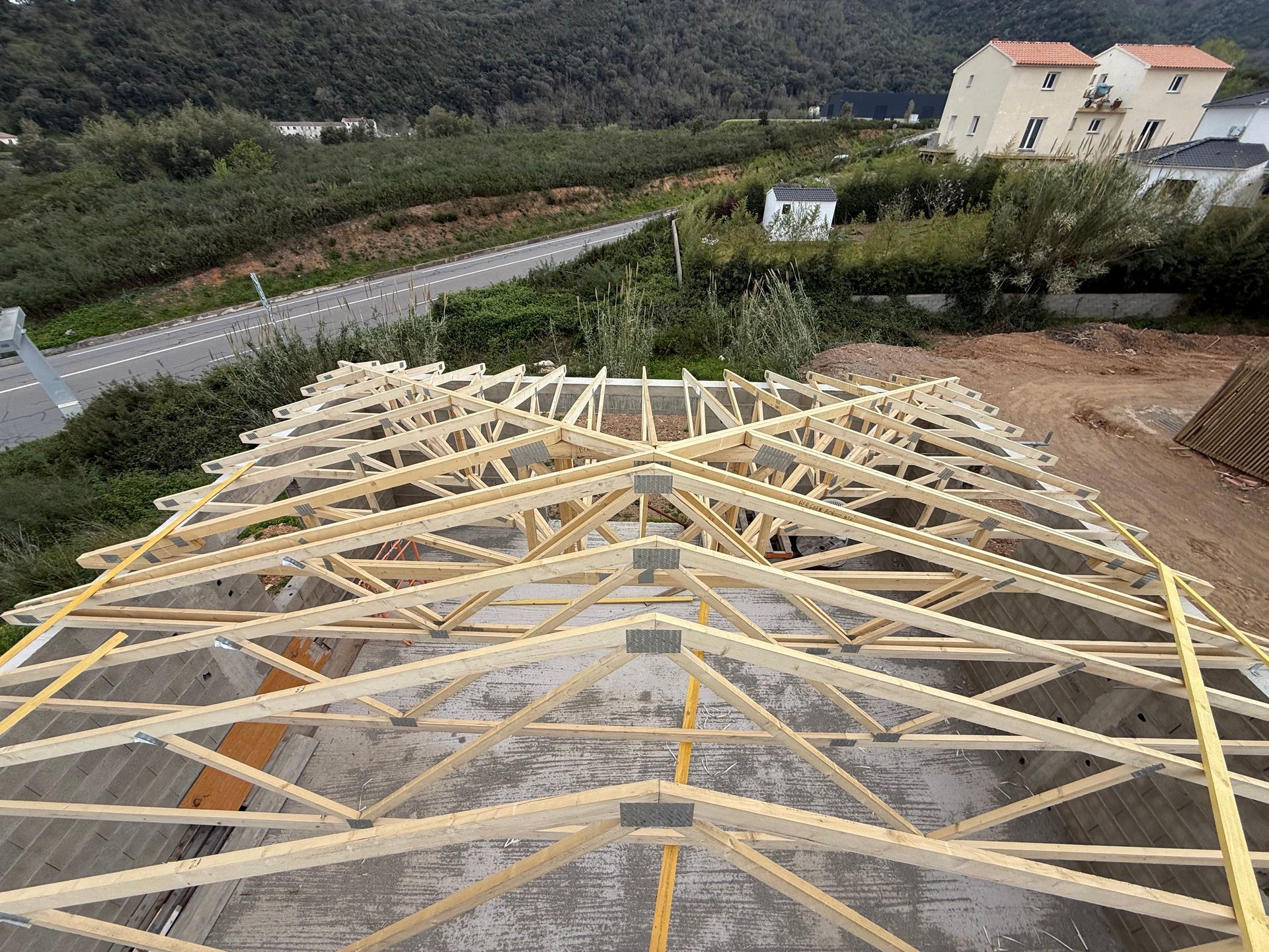Charpente de toit en bois en construction sur un terrain.