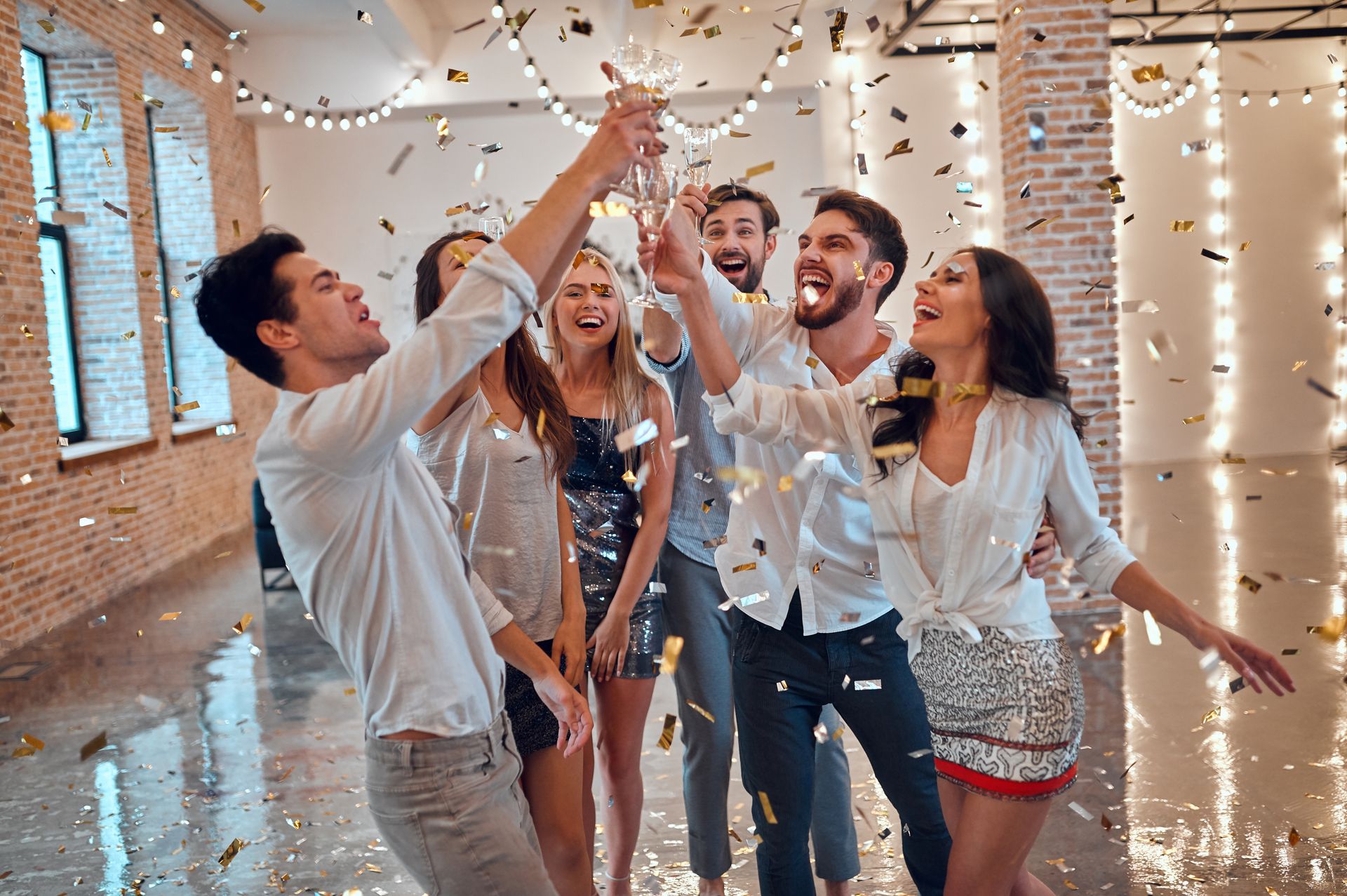 Groupe de personnes en fête, confettis, coupes de champagne levées, ambiance festive et joyeuse